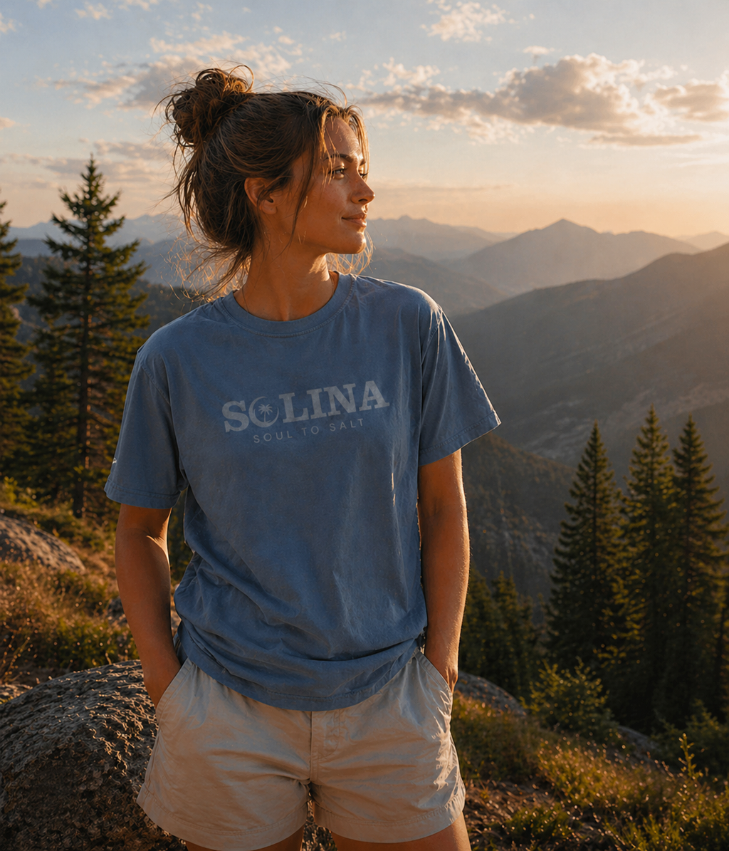 Person wearing a blue t-shirt with 'Solina' logo on a mountain landscape